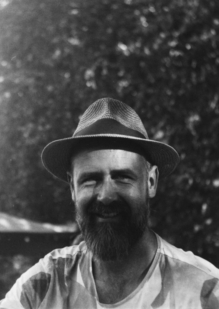 Portrait en noir et blanc d’un homme barbu au chapeau, souriant